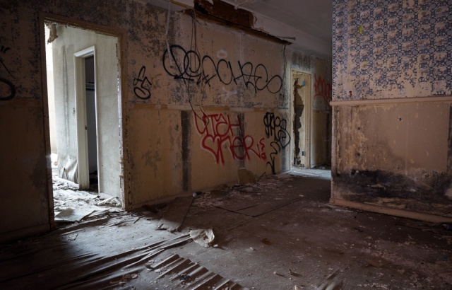 Interior of building with rotted unsafe wooden floors, black mold and damaged wallpaper