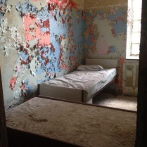 Patient room with two beds and colorful peeling paint on walls